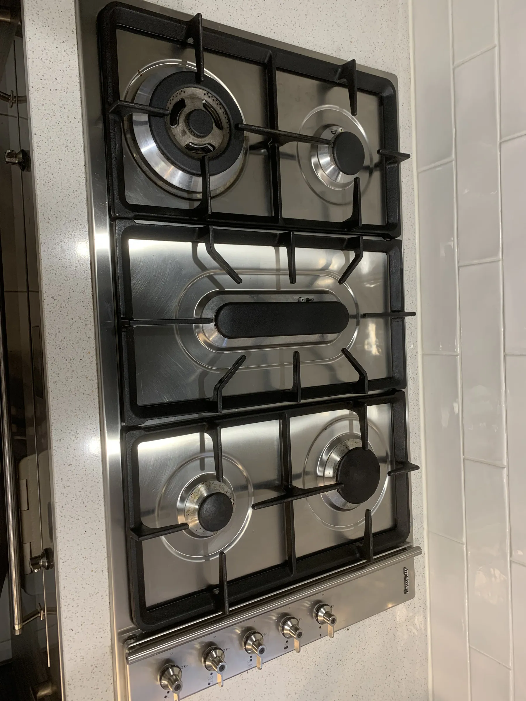 The same gas cooktop after cleaning, with clean grates and polished stainless steel